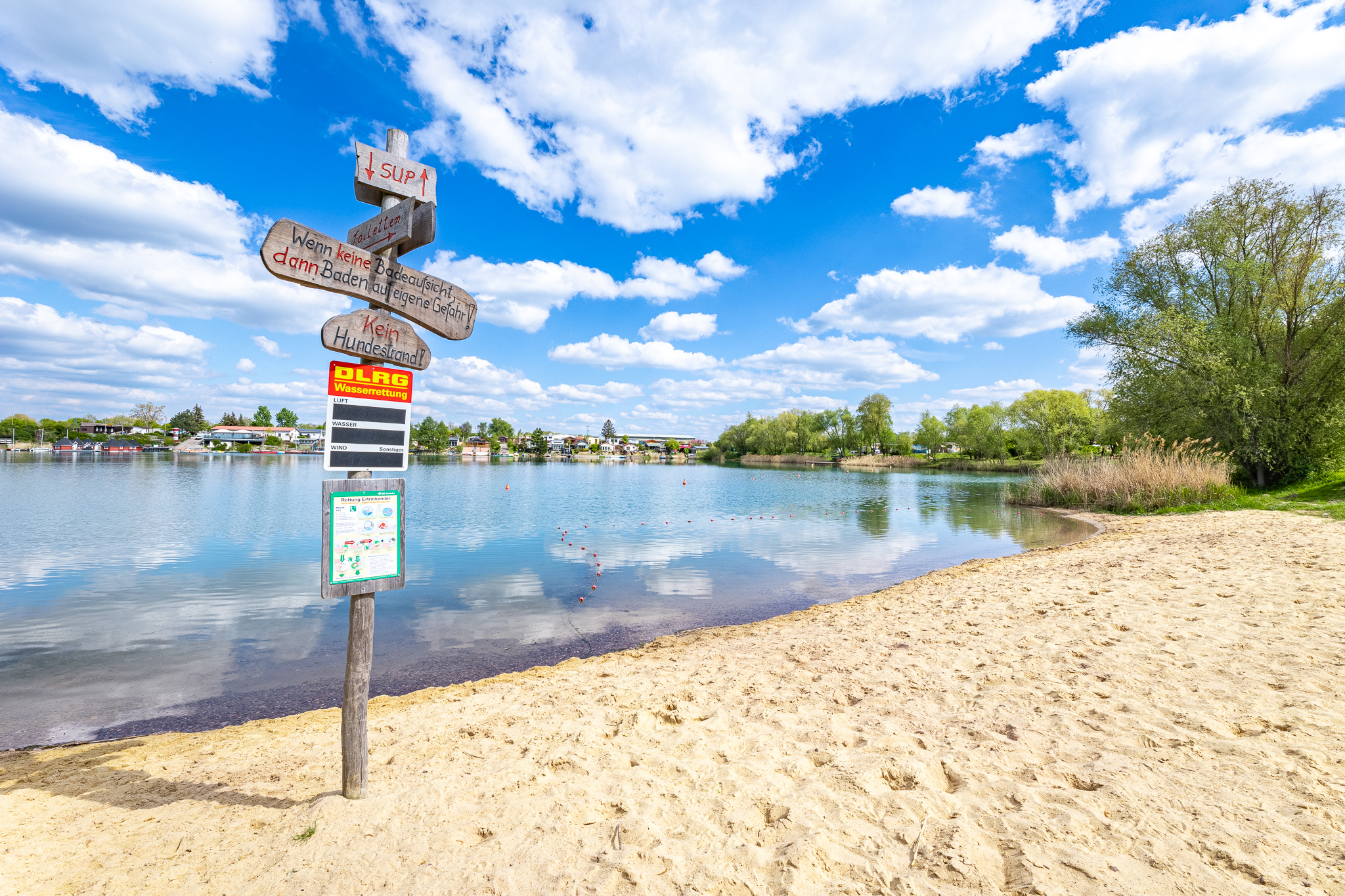 Wegweiser am Strand mit Blick auf den See